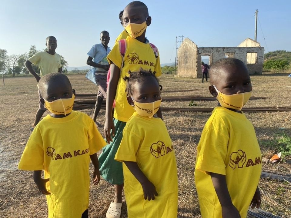 3 kids standing in line with face masks on.