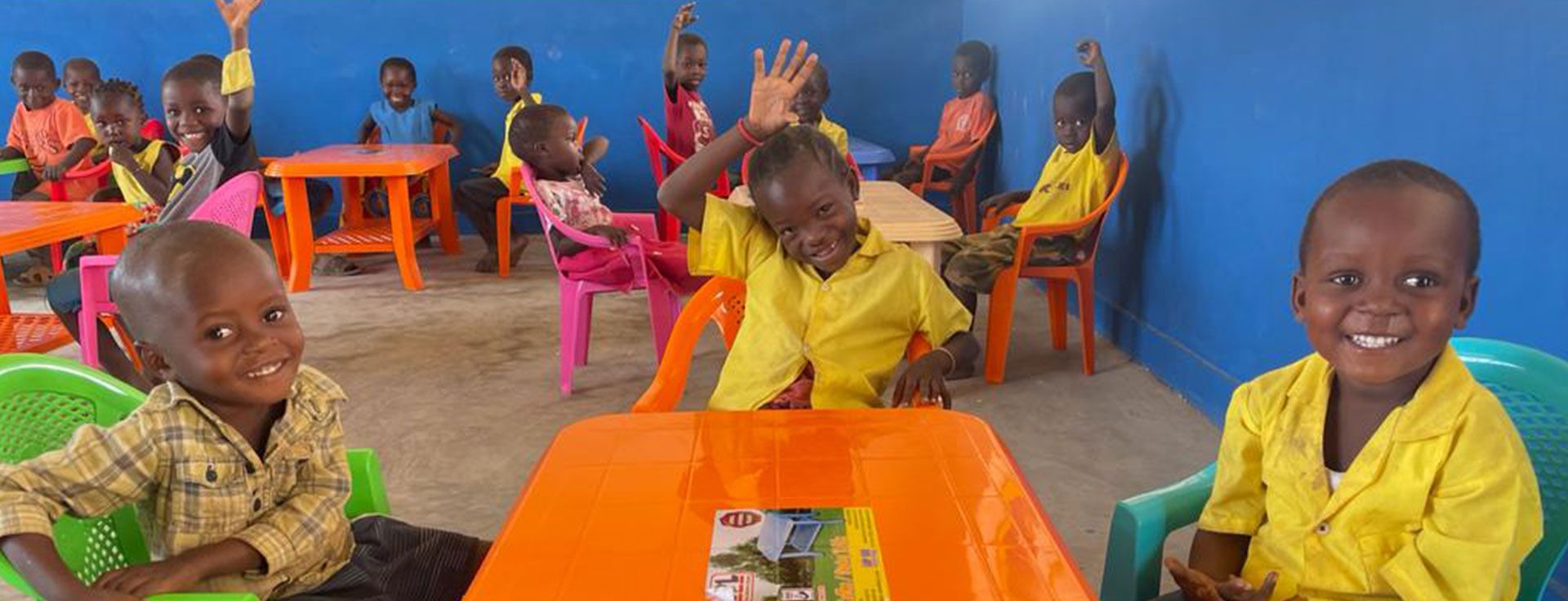Smiling students raising their hands in a new AM Kares classroom